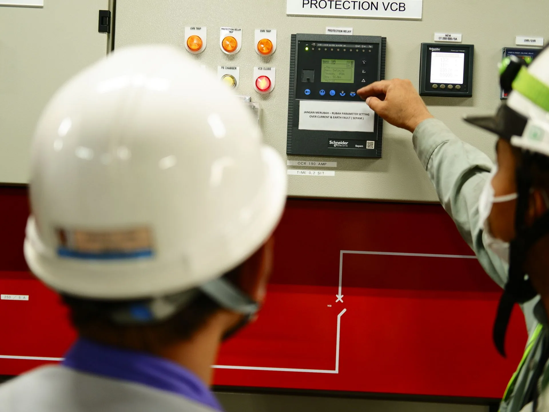 Deux techniciens en casque devant le pupitre de commande d’un équipement.