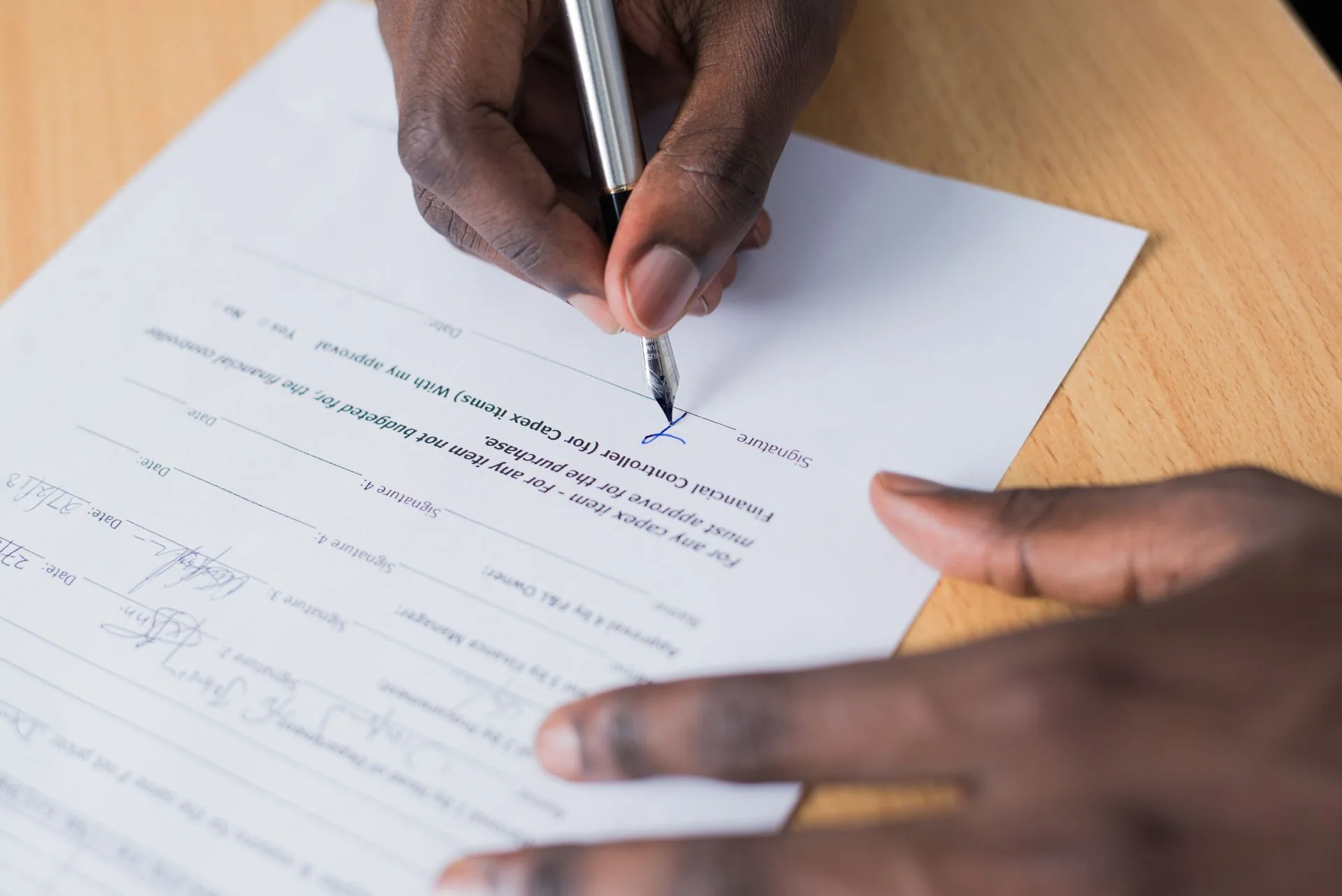 Une personne signe un document sur un bureau.